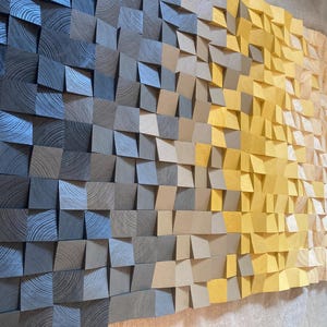 May include: A wall art piece made of wood tiles in shades of blue, brown, yellow, and beige. The tiles are arranged in a staggered pattern, creating a textured and dimensional effect.