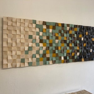 Pu&ograve; includere: Un'opera d'arte da parete realizzata con quadrati di legno in varie tonalit&agrave; di marrone, verde e beige. I quadrati sono disposti in uno schema geometrico, creando un design moderno e astratto.