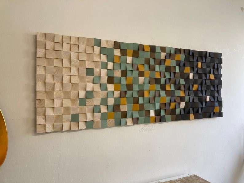 Pu&ograve; includere: Un'opera d'arte da parete realizzata con quadrati di legno in varie tonalit&agrave; di marrone, verde e beige. I quadrati sono disposti in uno schema geometrico, creando un design moderno e astratto.