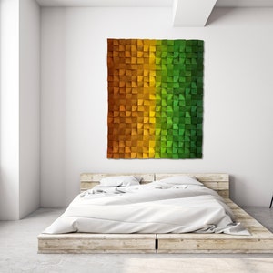 May include: A large, rectangular wall art piece made of small, square wooden blocks. The blocks are arranged in a gradient of colors, transitioning from orange to yellow to green. The artwork is mounted above a bed.