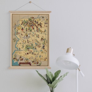 Może przedstawiać: Antyczna, ilustrowana mapa Arizony w drewnianej ramie. Mapa zawiera kreskówkowe ilustracje zabytków i punktów orientacyjnych w całym stanie. Mapa nosi tytuł "Arizona U.S.A."