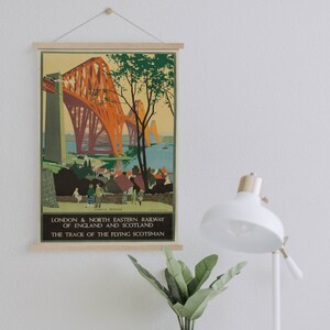 Op de afbeelding: Een vintage reisposter voor de London & North Eastern Railway van Engeland en Schotland. De poster toont een kleurrijke illustratie van de Forth Bridge, een rode stalen vakwerkbrug over de Firth of Forth in Schotland. De tekst op de poster luidt "Forth Bridge", "London & North Eastern Railway of England and Scotland" en "The Track of the Flying Scotsman".