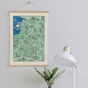Puede incluir: Una impresión de mapa vintage de Rolling Hills, un suburbio de Los Ángeles, California. El mapa está impreso en papel crema con un esquema de color verde y azul. El mapa está enmarcado con un marco de madera y colgado en una pared blanca.