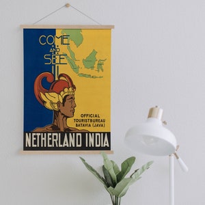 Op de afbeelding: Een vintage reisposter die reclame maakt voor een reis naar "Nederlands-Indië". De poster toont een kaart van de eilanden, een gestileerde illustratie van een persoon met een kroon en de tekst "Kom en zie".