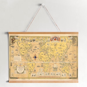 May include: A vintage world map print with a yellow background and colorful illustrations of ships, animals, and people. The map is framed in a wooden frame and is hanging on a white wall.