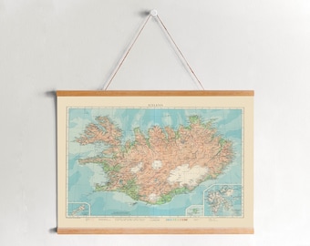 Könnte beinhalten: Eine Vintage-Karte von Island in einem Holzrahmen, die an einer weißen Wand hängt. Die Karte zeigt die Küstenlinie der Insel, Berge und Flüsse. Der Titel "Island" ist oben auf der Karte gedruckt.