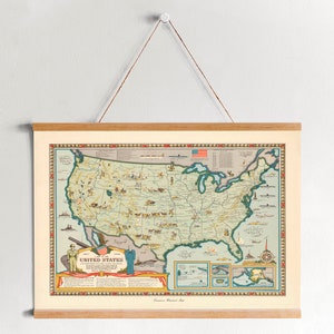 May include: A vintage map of the United States with a light blue background and a detailed illustration of the country's geography, including major cities, rivers, and mountains. The map is framed in a wooden frame and is hanging on a white wall.