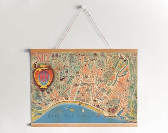 May include: A vintage map of Nice, France, displayed on a wooden frame. The map features detailed illustrations of the city's layout, including streets, buildings, and the coastline. The map is suspended by a string and is a decorative piece.