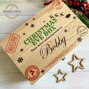 May include: A wooden Christmas Eve box, engraved with the name "Bobby" and festive Christmas designs. The box includes snowflakes, a reindeer mail stamp, and the text "Christmas Eve Box." Two wooden star cutouts are placed beside the box.