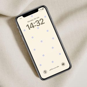 May include: A smartphone displaying a light beige background with a digital clock reading 14:32, the date Monday, 29 July, and a pattern of small blue flowers. The text "with love main atelier" is at the bottom of the screen.