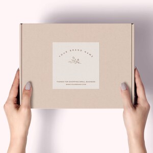 Pu&ograve; includere: Una scatola di cartone beige con un'etichetta bianca con la scritta "YOUR BRAND NAME" e un motivo floreale. La scatola &egrave; tenuta da due mani. L'etichetta include anche il testo "THANKS FOR SHOPPING SMALL BUSINESS" e un indirizzo web.