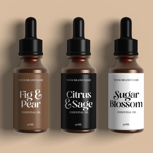 Op de afbeelding: Drie bruine glazen flessen met druppelaars en witte etiketten. De etiketten hebben zwarte tekst die "YOUR BRAND NAME", "Fig & Pear ESSENTIAL OIL", "Citrus & Sage ESSENTIAL OIL" en "Sugar Blossom ESSENTIAL OIL" luidt. Elke fles bevat 50 ml etherische olie.