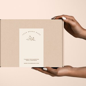 Pu&ograve; includere: Una scatola di cartone beige con un'etichetta color crema. L'etichetta presenta un motivo floreale e il testo "YOUR BRAND NAME". C'&egrave; anche scritto "THANKS FOR SHOPPING SMALL BUSINESS" e un indirizzo web.