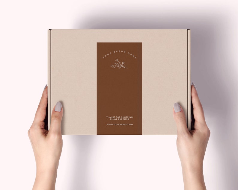 Pu&ograve; includere: Una scatola di cartone beige con un'etichetta rettangolare marrone. L'etichetta presenta il testo "YOUR BRAND NAME" e "THANKS FOR SHOPPING SMALL BUSINESS" con un design floreale. &Egrave; visibile anche l'indirizzo del sito web.