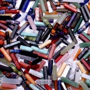 May include: A collection of various gemstone crystals in shades of red, pink, green, black, white, and blue. The crystals are of different sizes and shapes, with a hexagonal or rectangular form.