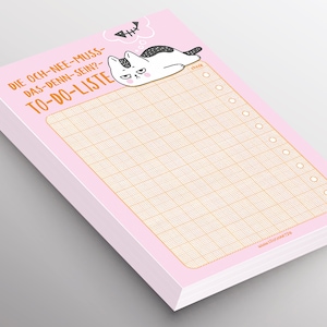 Könnte beinhalten: Rosa To-Do-Liste Notizblock mit einer Illustration einer schwarz-weißen Katze. Die Katze liegt mit einer Gedankenblase über dem Kopf, in der "Fisch" steht. Der Text auf dem Notizblock lautet "Die och-nee-muss-das-denn-sein? To-do-Liste".