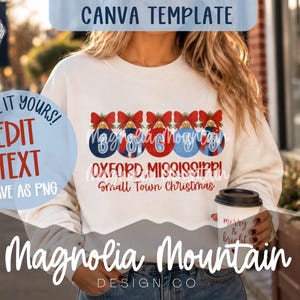 May include: A white crewneck sweatshirt featuring a graphic of five Christmas ornaments with red bows, each containing a number. Below the ornaments, the text reads OXFORD, MISSISSIPPI and Small Town Christmas in red and blue lettering.