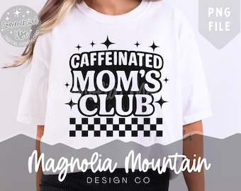 Op de afbeelding: Wit T-shirt met de tekst "CAFFEINATED MOM'S CLUB" in zwarte, vette letters. Het ontwerp bevat steraccenten en een dambordpatroon. De merknaam "Magnolia Mountain Design Co" staat eronder.