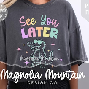 Puede incluir: Camiseta gris oscuro con el texto "See You Later" en colores pastel sobre un cocodrilo de dibujos animados con gafas de sol. La camiseta también presenta el texto "Magnolia Mountain Design Co."
