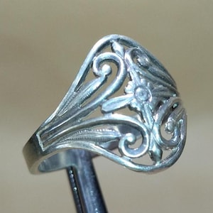 May include: A silver filigree ring with a delicate floral design. The ring is open on one side and has a smooth, polished finish.