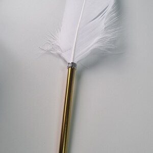 May include: A gold and white feather pen with a silver band. The pen is on a white background.