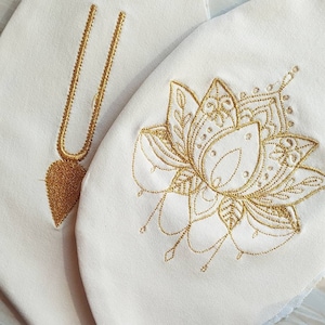 May include: Two white fabric panels with gold embroidery. One panel features a heart-shaped pendant on a chain, the other features a stylized floral design.