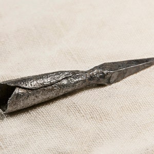 Könnte beinhalten: Eine Metallpfeilspitze mit einem ausgehöhlten Sockel, wahrscheinlich für die Jagd oder die Kriegsführung verwendet.