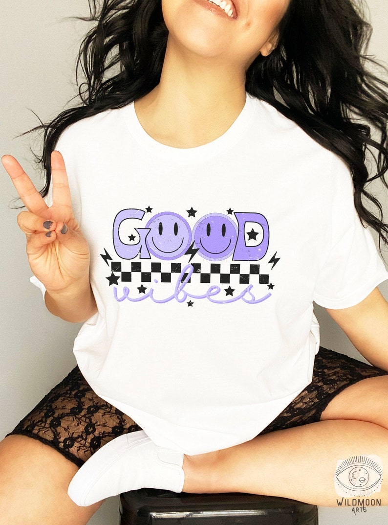 May include: White t-shirt with a purple graphic that says "GOOD" with two purple smiley faces and "vibes" with black and white checkered pattern and stars.