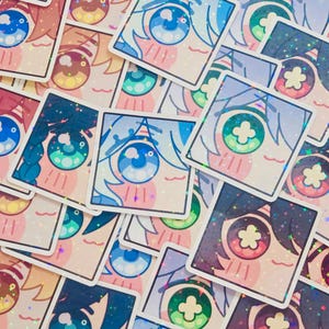 Pode incluir: Uma cole&ccedil;&atilde;o de autocolantes quadrados com desenhos de olhos em estilo anime. Os autocolantes apresentam v&aacute;rias cores de olhos, incluindo azul, verde e castanho, com c&iacute;lios e cabelo detalhados. Os autocolantes t&ecirc;m um acabamento hologr&aacute;fico e brilhante.