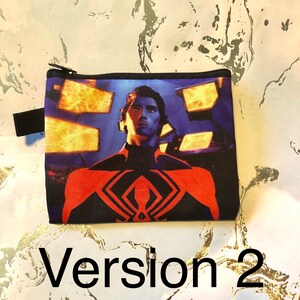 Puede incluir: Una bolsa negra con cremallera que muestra una imagen colorida de un superh&eacute;roe con un traje rojo y negro. El fondo es un dise&ntilde;o abstracto azul y naranja. La bolsa tiene una cremallera negra y una correa negra.