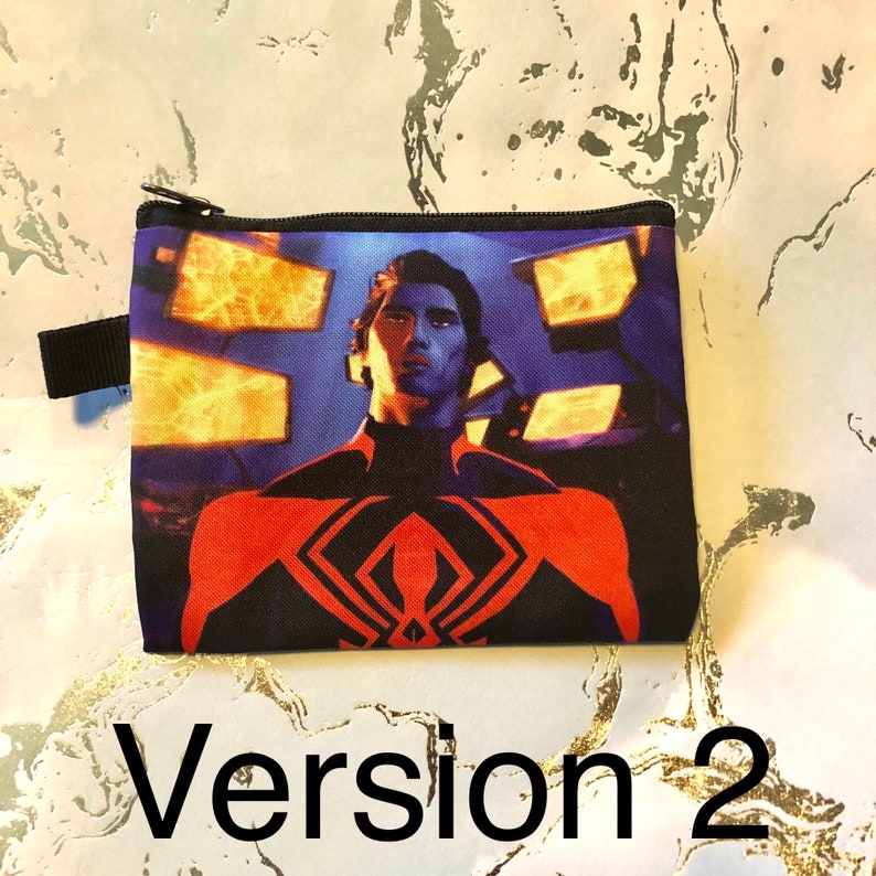 Puede incluir: Una bolsa negra con cremallera que muestra una imagen colorida de un superh&eacute;roe con un traje rojo y negro. El fondo es un dise&ntilde;o abstracto azul y naranja. La bolsa tiene una cremallera negra y una correa negra.