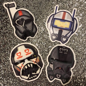 May include: Four black and white cartoon character stickers with red hearts and white accents. The characters are wearing helmets and have different facial expressions.