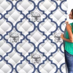 May include: A white and blue patterned wallpaper with a repeating design of a blue quatrefoil and a gray and white illustration of a Star Wars clone trooper helmet.