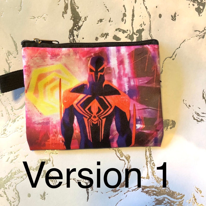 Puede incluir: Una peque&ntilde;a bolsa con cremallera con un dise&ntilde;o colorido que presenta a un superh&eacute;roe con un traje negro y naranja con un s&iacute;mbolo de ara&ntilde;a en el pecho. El fondo es una mezcla de rosa, amarillo y azul.