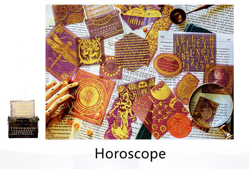 May include: A collection of decorative stickers and ephemera with a horoscope theme. The stickers feature gold foil accents on a burgundy background, with images of a dragonfly, sun, and other celestial designs. A vintage typewriter is also present.