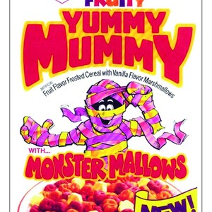 May include: A box of Fruity Yummy Mummy cereal with a cartoon mummy holding a bowl of the cereal. The cereal is a mix of red, yellow, and orange fruit-flavored shapes with vanilla marshmallows. The box says "New!" and "With Monster Mallows".