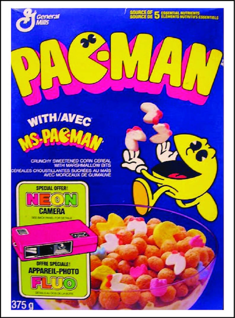 May include: A box of Pac-Man cereal with a yellow Pac-Man character on the front. The cereal is a mix of yellow, white, and pink pieces. The box also features a special offer for a neon camera.