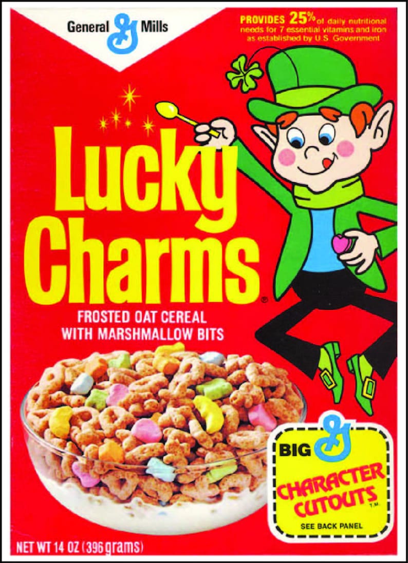 Puede incluir: Una caja de cereal Lucky Charms con un duende de dibujos animados sosteniendo un amuleto en forma de coraz&oacute;n. La caja es roja con letras amarillas y presenta un taz&oacute;n de cereal con malvaviscos. El texto en la caja dice "Lucky Charms Frosted Oat Cereal with Marshmallow Bits" y "Provides 25% of daily nutritional needs for 7 essential vitamins and iron as established by U.S. Government".