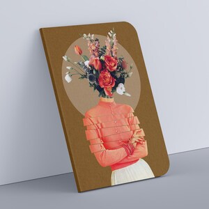 May include: A brown notebook with a floral collage on the cover. The collage features a woman with a bouquet of red, pink, and white flowers in place of her head. The background is a light brown circle.