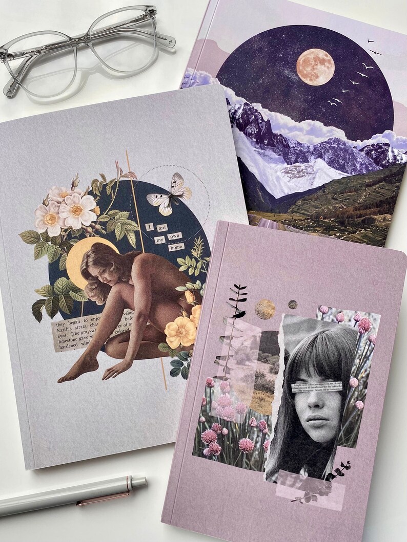 May include: Three different notebooks with collage art covers. The first notebook has a woman sitting with a butterfly and flowers. The second notebook has a mountain scene with a moon and stars. The third notebook has a woman's face with flowers and a quote that says "I am my own home".