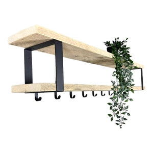 May include: A wooden shelf with black metal brackets and hooks. The shelf is mounted to the wall and has a potted plant hanging from it.