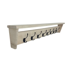 Puede incluir: Un perchero de pared de madera de color claro con una balda y ocho ganchos de metal negro. El perchero est&aacute; hecho de madera de color claro y tiene un dise&ntilde;o simple y minimalista. Los ganchos est&aacute;n espaciados uniformemente.