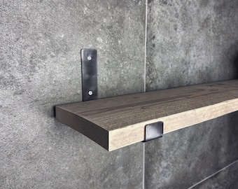 May include: A wooden shelf with black metal brackets. The shelf is mounted to a grey tiled wall.