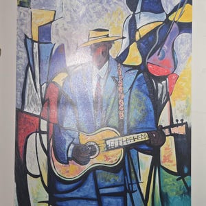 Könnte beinhalten: Abstrakte Malerei eines Musikers, der Gitarre spielt. Das Kunstwerk zeigt einen Mann in einem blauen Anzug und einem gelben Hut. Der Hintergrund hat geometrische Formen in Gelb, Blau und Rot.