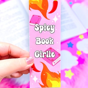 Op de afbeelding: Roze boekenlegger met een rode peper, vlammen en een gesloten boek. De boekenlegger heeft de tekst "Spicy Book Girlie" in een retro-lettertype.