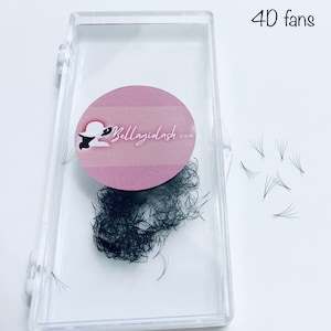 May include: A clear plastic container with a pink circle sticker that says "Bellagiolash.com" and a small woman wearing a hat. The container holds a bunch of black eyelash extensions. There are also a few individual eyelash extensions on a white surface. The text "4D fans" is written in black on the white surface.