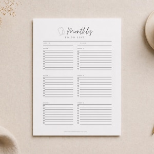 Könnte beinhalten: Eine weiße monatliche To-Do-Liste mit den Worten "Monthly To Do List" oben. Die Liste ist in Abschnitte für jede Woche unterteilt, mit Platz für Ziele und Aufgaben. Ein Stift und eine Tasse Kaffee befinden sich im Hintergrund.