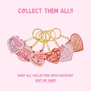 May include: A set of six pink and red heart-shaped keychains with gold chains. The keychains feature various phrases, including "This Barbie is her own BOSS", "Mom, I am a rich man", "You're doing amazing sweetie", and "I'm just a girl".