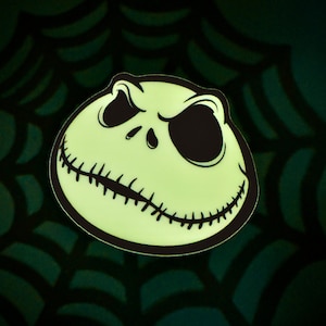 May include: A glow-in-the-dark Jack Skellington face from The Nightmare Before Christmas. The face is white with black eyes and a stitched mouth.