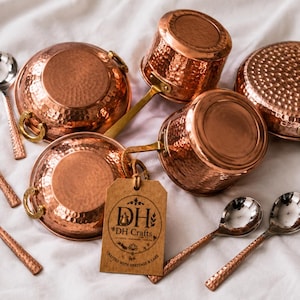May include: A collection of hammered copper cookware including two round pots with side handles, two saucepans with long handles, and five silver-toned spoons with textured copper handles. A brown paper tag displays the text DH DH Crafts.
